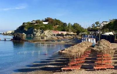 a beach with chairs and straw umbrellas and the water at me gusta suite by the sea in Anavissos