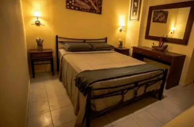 a bedroom with a bed and two tables and a mirror at me gusta suite by the sea in Anavissos