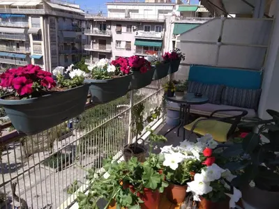 a balcony with potted plants and tables and buildings at Rooms in Central Athens in Athens