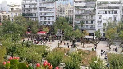 a group of people walking in a city with buildings at Rooms in Central Athens in Athens