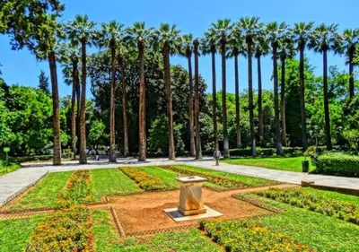 a garden with palm trees and a statue in the middle at Syntagma Elysan Urban Stays in Athens