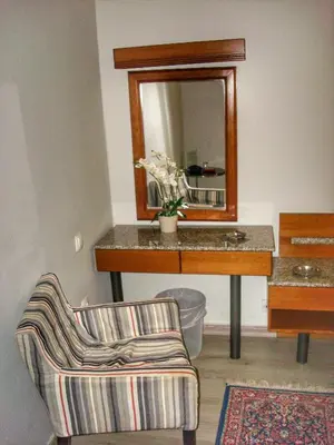 a bathroom with a sink and a mirror and a chair at Park Hotel in Athens