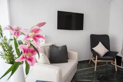 a living room with a white couch and pink flowers at Living near Acropolis by Sylvia Staikou 2nd & 3d floor in Athens