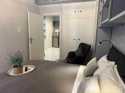 a bedroom with a bed and a black chair at Living near Acropolis by Sylvia Staikou 2nd & 3d floor in Athens