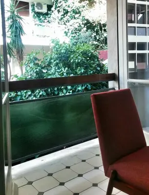 a red chair sitting on a balcony with a window at Central new Kolonaki apartment in Athens