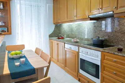 a kitchen with wooden cabinets and a table with a bowl of fruit at Zeas Apartment in Piraeus
