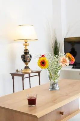 a vase of flowers on a table with a lamp at Zeas Apartment in Piraeus