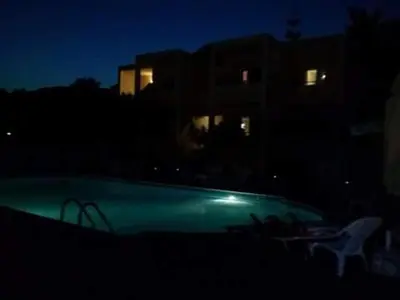 a swimming pool at night with a building in the background at Anna Studios in Agia Marina Aegina