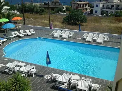 a large swimming pool with chairs and umbrellas at Anna Studios in Agia Marina Aegina
