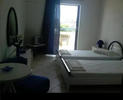 a bedroom with two beds and a table and a window at Anna Studios in Agia Marina Aegina