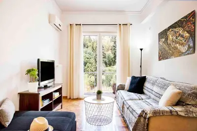 a living room with a couch and a tv at Unique views of Filopapou hill in Acropolis Area! in Athens