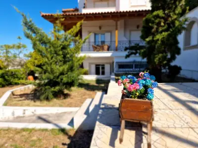 a bench with flowers in front of a house at The Mirador Boutique Villa with Scenic Sea View in Porto Rafti