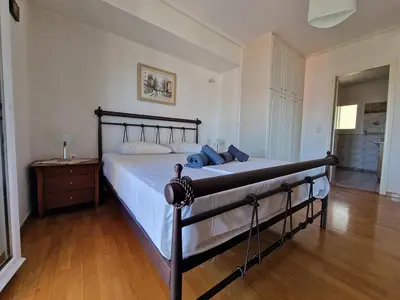 a large bed in a bedroom with a wooden floor at The Mirador Boutique Villa with Scenic Sea View in Porto Rafti