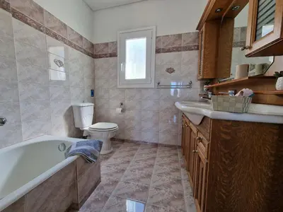 a bathroom with a tub and a toilet and a sink at The Mirador Boutique Villa with Scenic Sea View in Porto Rafti