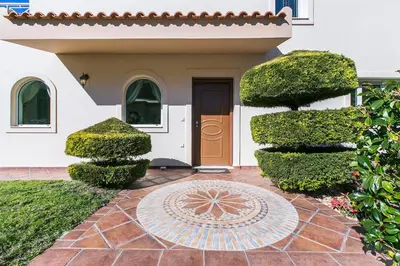 a front door of a house with hedges and a tile floor at Villa Melia Athenian Riviera in Sounio