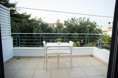 a white table and two chairs on a balcony at Porto Rafti view by Akroploro in Porto Rafti
