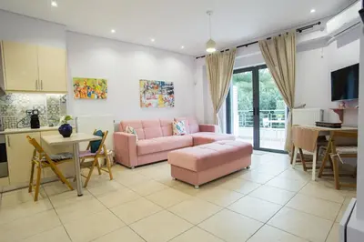 a living room with a pink couch and a kitchen at Porto Rafti view by Akroploro in Porto Rafti
