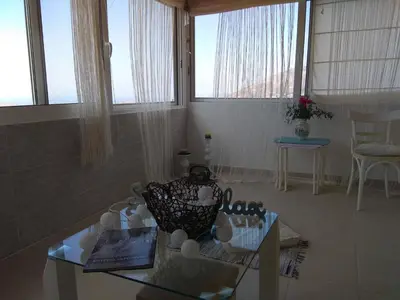 a living room with a glass table and windows at Outstanding Panoramic View, 10΄ beach, 20΄ airport in Ólimbos