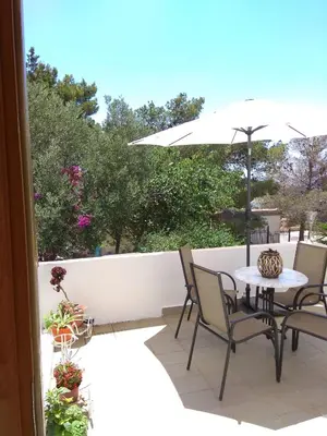 a patio with a table and chairs and an umbrella at Outstanding Panoramic View, 10΄ beach, 20΄ airport in Ólimbos