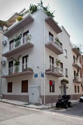 a white building with balconies and a motorcycle parked in front at Exarcheia House in Athens