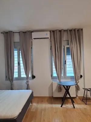 a bedroom with a bed and a table and windows at Exarcheia House in Athens
