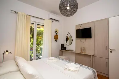 a bedroom with a white bed and a tv at Hadrian by Heloni Apartments in Athens