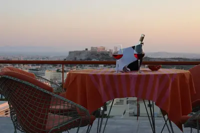 a table with a bottle of wine and two glasses at Acropolis view penthouse in Athens