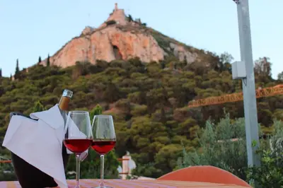 two glasses of wine sitting on a table with a mountain at Acropolis view penthouse in Athens