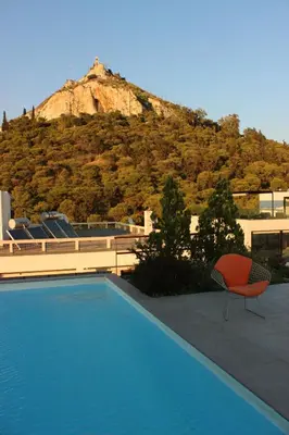 a swimming pool with a chair and a mountain at Acropolis view penthouse in Athens