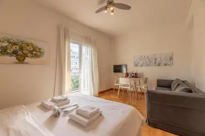 a bedroom with a bed and a couch and a window at Top sightseeing 3rd floor studio on a paved road! in Athens