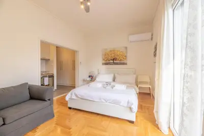 a white bedroom with a bed and a couch at Top sightseeing 3rd floor studio on a paved road! in Athens