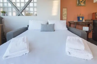 a white bed with white towels on top of it at 5th flr Boho studio @ Exarheia w/ balcony in Athens