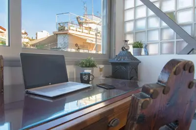 a laptop computer sitting on a glass desk with a window at 5th flr Boho studio @ Exarheia w/ balcony in Athens