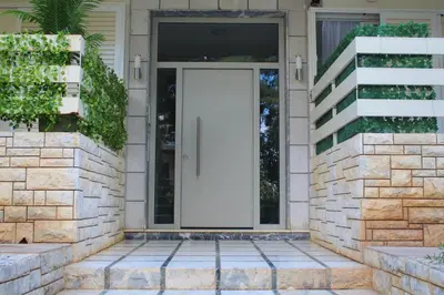a white door on a stone house with stairs at Bright and Peaceful Apartment near Varkiza beach in Varkiza