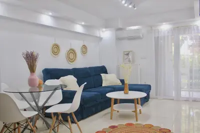 a living room with a blue couch and a table at Bright and Peaceful Apartment near Varkiza beach in Varkiza