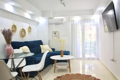 a living room with a blue couch and a table at Bright and Peaceful Apartment near Varkiza beach in Varkiza