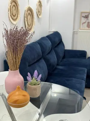 a living room with a blue couch and a glass table at Bright and Peaceful Apartment near Varkiza beach in Varkiza