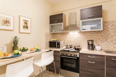 a kitchen with a stove and some white chairs at Museum of Modern Art Rooms in apartment, next to metro Suggrou Fix, walk to Acropolis in Athens