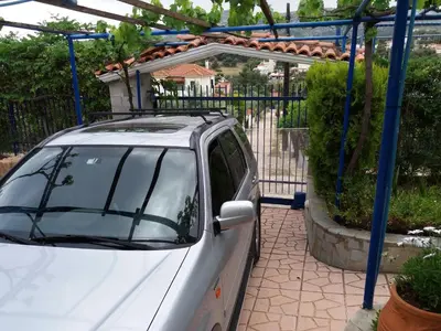 a white car parked in front of a gate at Aliki House in Porto Rafti