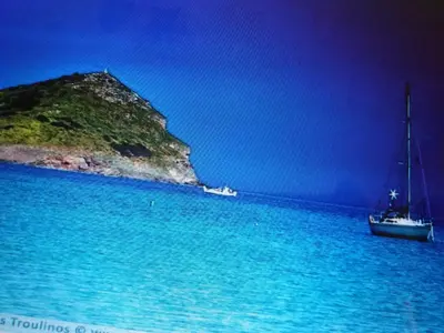 two boats in the water next to an island at Aliki House in Porto Rafti