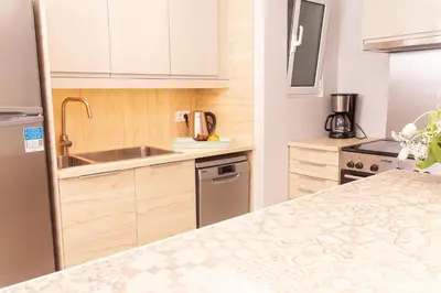 a kitchen with white cabinets and a counter top at Sweet Suite Flora in Vouliagmeni in Athens