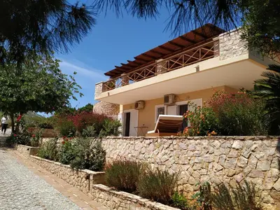a house on the side of a stone wall at Villa Vena in Palaiá Fókaia