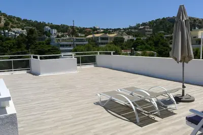a patio with two chairs and an umbrella on a roof at Athens Riviera Loft in Athens