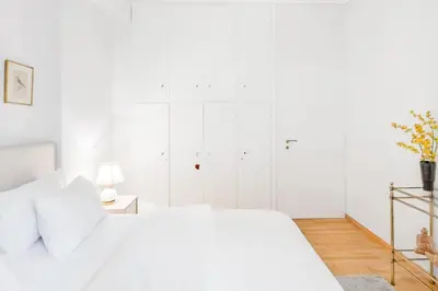 a white bedroom with a white bed and white cabinets at Koukaki Apartment with a Sunny Balcony, near the Acropolis in Athens