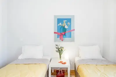 two beds in a room with a picture on the wall at Koukaki Apartment with a Sunny Balcony, near the Acropolis in Athens