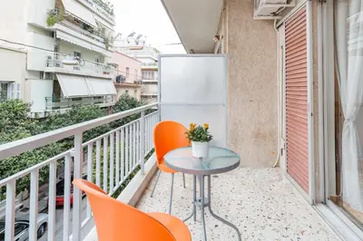a balcony with orange chairs and a table and a refrigerator at Koukaki Apartment with a Sunny Balcony, near the Acropolis in Athens