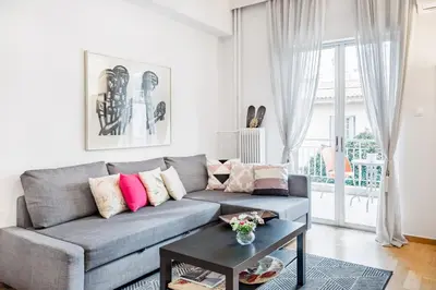 a living room with a gray couch and a table at Koukaki Apartment with a Sunny Balcony, near the Acropolis in Athens