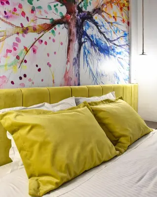 a bed with yellow pillows in front of a painting at Lycabettus Exclusive Apartments in Athens