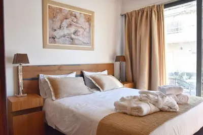 a bedroom with a bed with white sheets and a window at Lycabettus Exclusive Apartments in Athens