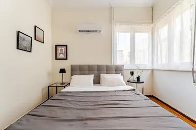 a large bed in a white room with two windows at 3BDR IDEAL CENTRAL ATHENIAN APT in Athens